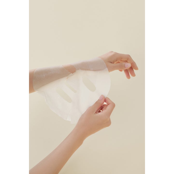 I'm from Rice Sheet mask 5 stk ansigtsmaske giver glød vist som en tynd hvid arkmaske holdt af hænder.
