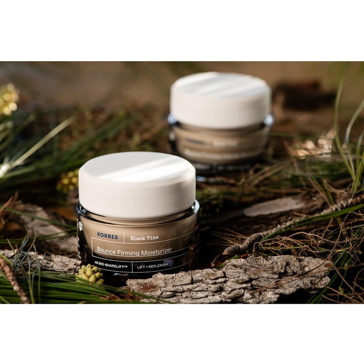 KORRES Black Pine 4D Bounce Firming Moisturizer 40 ml opstrammende dagcreme i mørk krukke på en naturlig skovbund