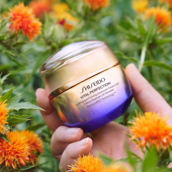 Shiseido Vital Perfection Advanced Soft Cream 50 ml i luksuriøs guld og lilla krukke blandt orange blomster