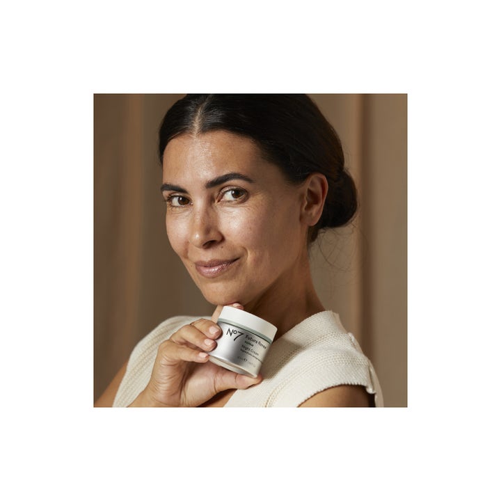 No7 Future Renew Repair Night Cream 50 ml reparerende nattkräm i sølvfarvet krukke holdt af en smilende kvinde.
