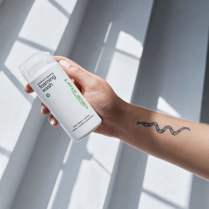 Dermalogica Clear Start Breakout Clearing Foaming Wash med salicylsyre i hvid flaske holdt af en tatoveret hånd