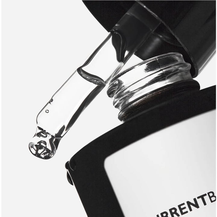 Currentbody Skin Green Tea Serum 30 ml fugtgivende serum med klar væske fra en glaspipette over en sort flaske