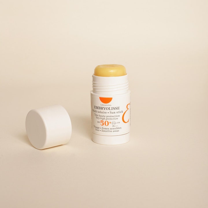 Embryolisse Sun Stick SPF50+ 15 g solbeskyttelse i hvid stift med gul balsam og et løst hvidt låg på lys baggrund