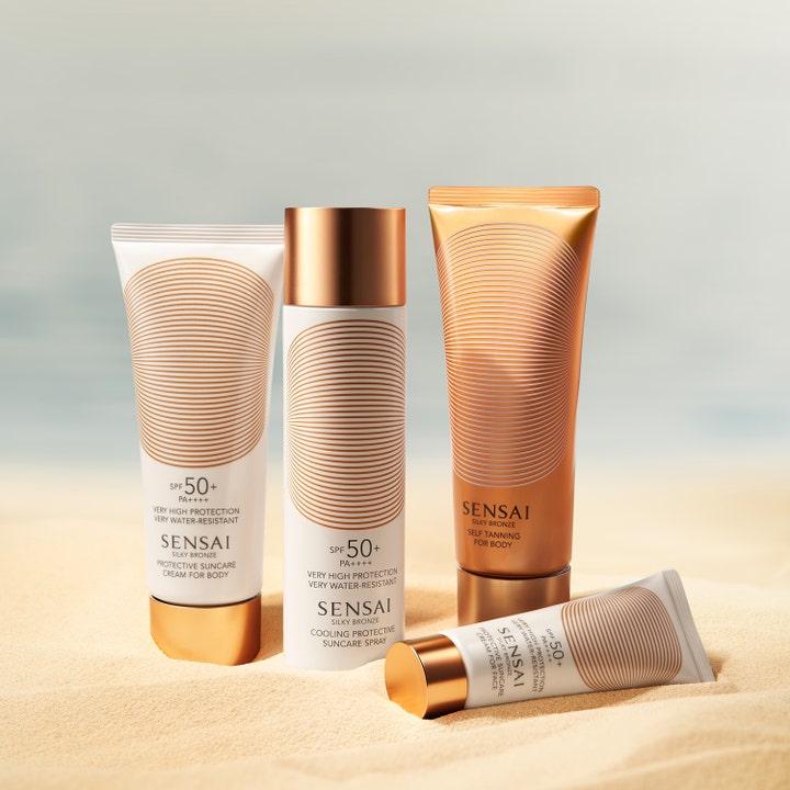 Sensai Silky Bronze Protective Cream Face SPF50+ 50 ml solcreme i hvid tube med guldlåg liggende i varmt sand