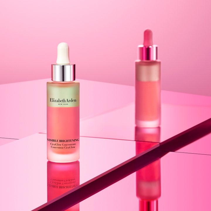 Elizabeth Arden Visible Brightening Cica Glow 30 ml serum i to-faset glasflaske på lyserød reflekterende baggrund