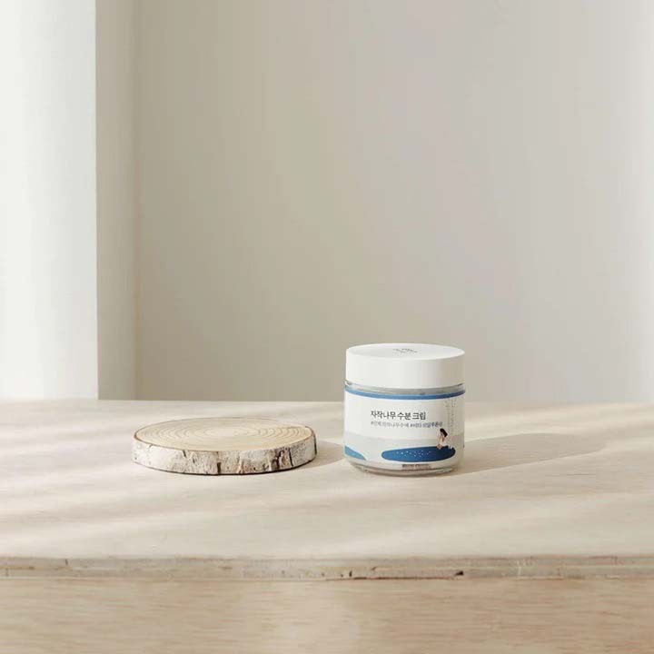 Round Lab Birch Juice Moisturizing Cream 80 ml fugtgivende ansigtscreme i krukke ved siden af en birketræsskive
