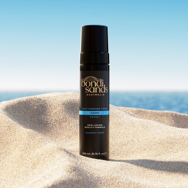 Bondi Sands Self Tanning Foam Dark 200 ml selvbruner i sort flaske der står i sandet på en solrig strand