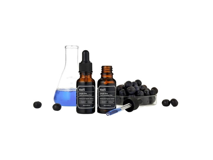 Klairs Midnight Blue Youth Activating Drop 20 ml serum ved siden af kolber og friske blåbær.