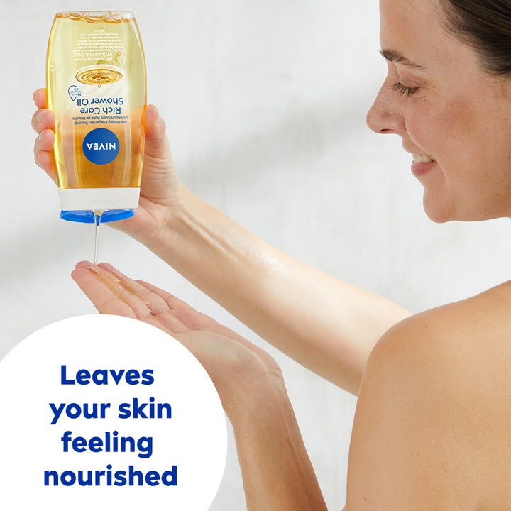 NIVEA Rich Caring Shower Oil 200 ml plejende badeolie hældes fra gennemsigtig flaske i hånden på en kvinde.