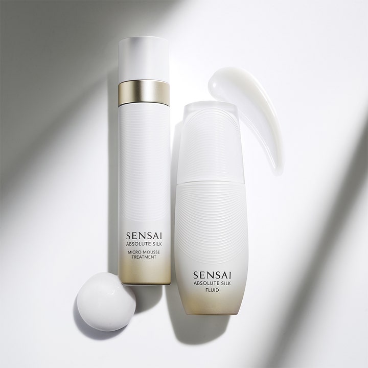 Sensai Absolute Silk Fluid 80 ml ansigtscreme med hvid mousse og let tekstur ved elegante hvide flasker