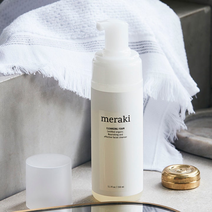 Meraki Cleansing Foam 150 ml økologisk rengøringsskum i en frostet flaske med hvid pumpe ved et hvidt håndklæde