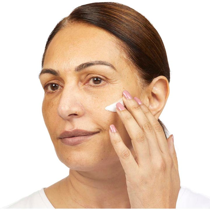 No7 Restore & Renew Night Cream 50 ml er en plejende nattkräm som en kvinde påfører på sin kind.