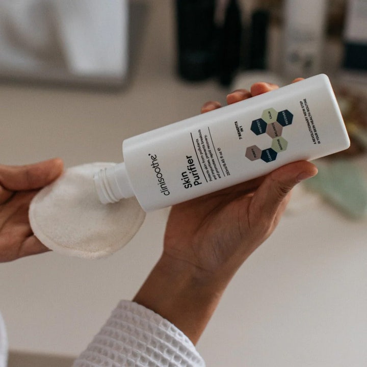 Clinisoothe Skin Purifier 250 ml toner der beroliger huden mens den hældes på en vatrondel fra hvid flaske.