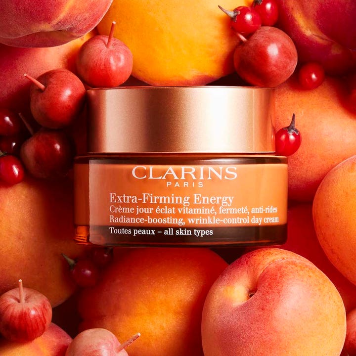 Clarins Extra-Firming Energy 50 ml opstrammende dagcreme i orange krukke omgivet af friske abrikoser og bær