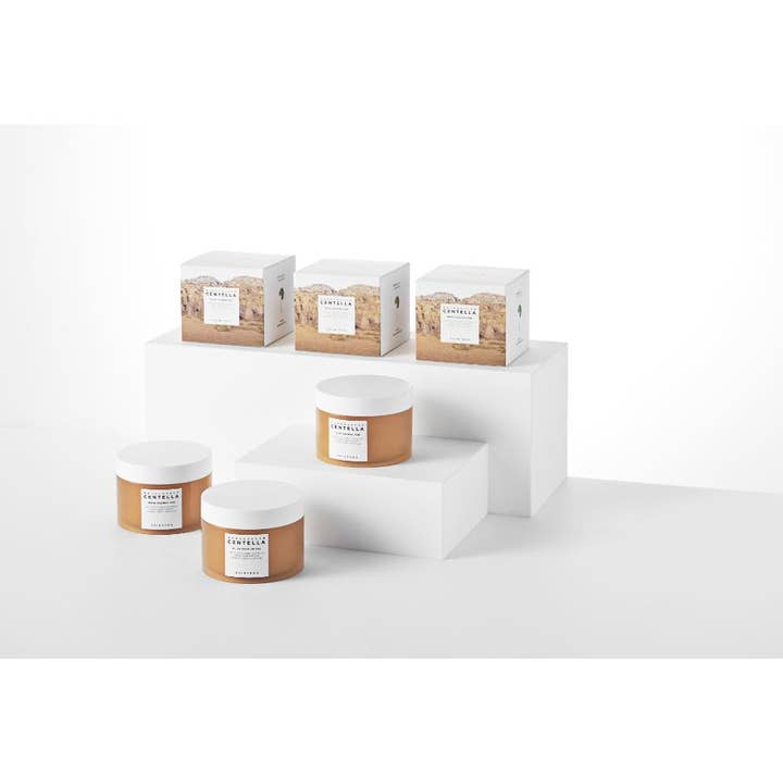SKIN1004 Madagascar Centella Quick Calming Pad 130 ml beroligende spot treatment i brune krukker og æsker på hvide podier