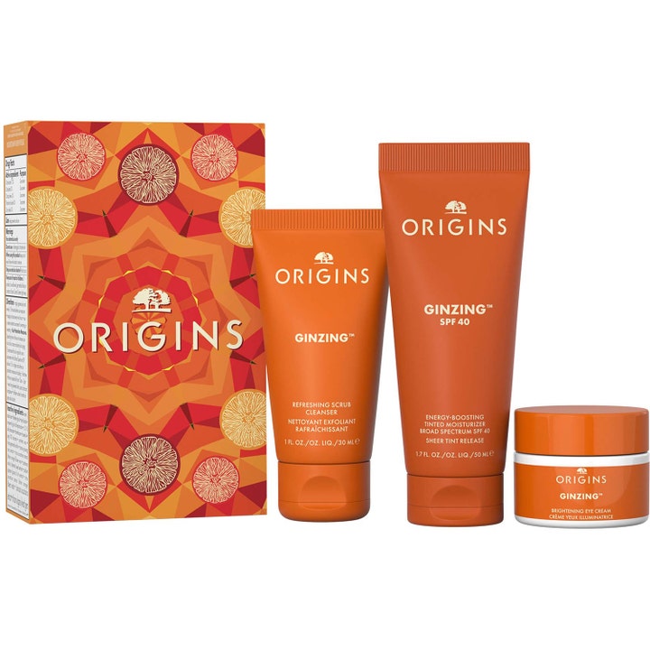 Origins GinZing gavesæt med energigivende ansigtspleje i orange tuber og hvid krukke foran en mønstret æske.