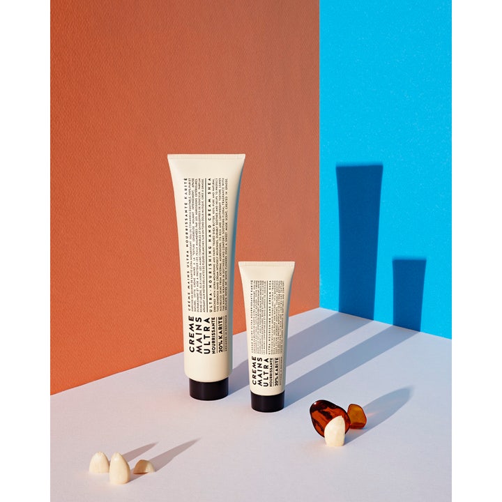 Compagnie de Provence Shea Butter Hand Cream 100 ml i tube med karitésmør mod en orange og blå baggrund