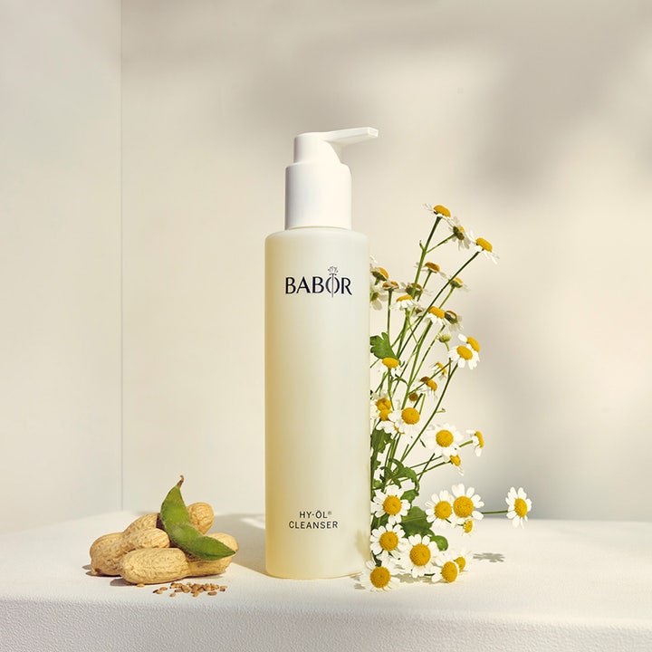 Babor HY-Öl Cleanser 200 ml fugtgivende renseolie i frostet flaske ved siden af kamilleblomster og jordnødder