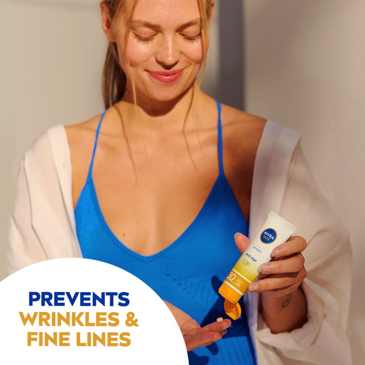 NIVEA Sun UV Face Anti Age Q10 Cream 50 ml solcreme mod rynker påføres af kvinde i sollys fra hvid tube.