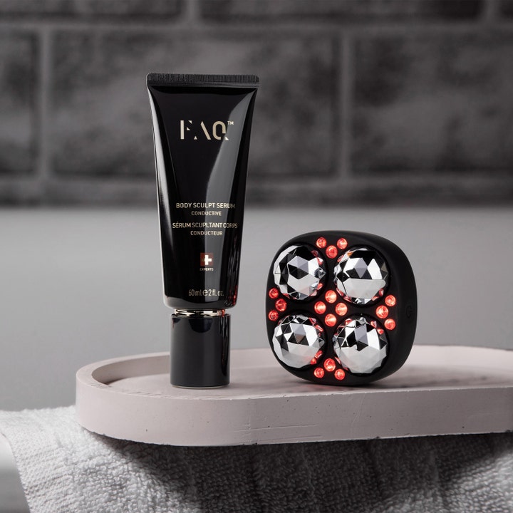 FAQ Swiss FAQ™ Body Sculpt Serum 60 ml opstrammende kropsserum i sort tube ved siden af enhed med rødt LED-lys