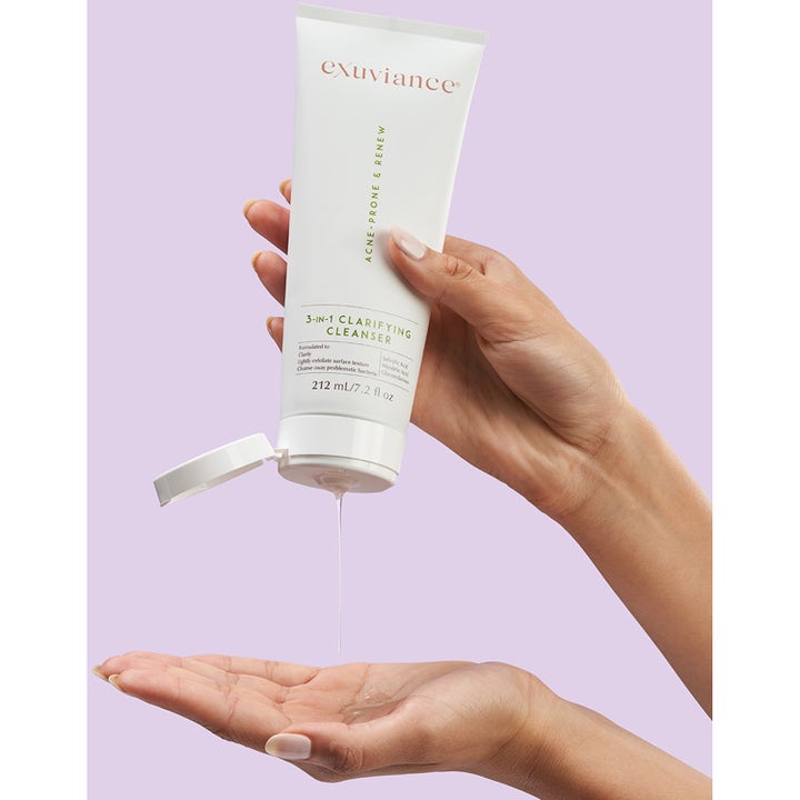 Exuviance 3-in-1 Clarifying Cleanser 212 ml ansigtsrens hvor klar gelé presses ud i hænderne mod lilla baggrund.