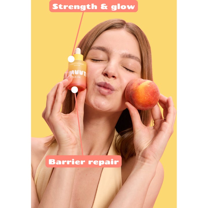 Smuuti Skin Peach Barrier Serum 30 ml barrierestyrkende ansigtsserum i orange flaske holdt af kvinde med fersken.