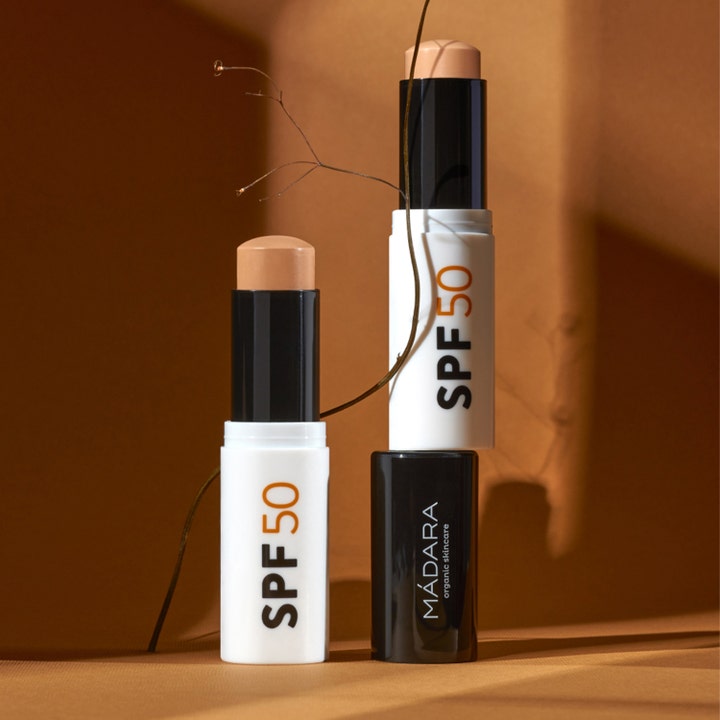 MÁDARA Mineral SPF50 Sunscreen Stick 12 g beskyttende mineral solcreme i hvid stift med beige tekstur og varm baggrund