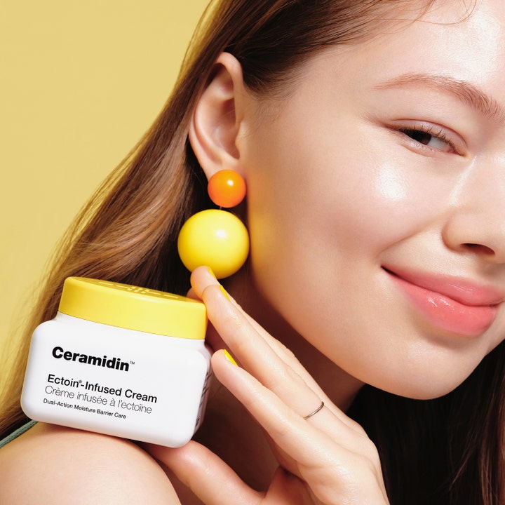 Dr.Jart+ Ceramidin Ectoin-Infused Cream 50 ml styrkende ansigtscreme i hvid krukke med gult låg holdt af smilende kvinde