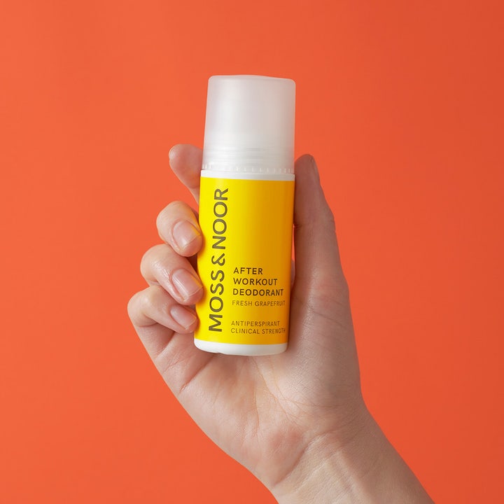 Moss & Noor After Workout Deodorant 60 ml mod sved holdes i hånden mod en orange baggrund