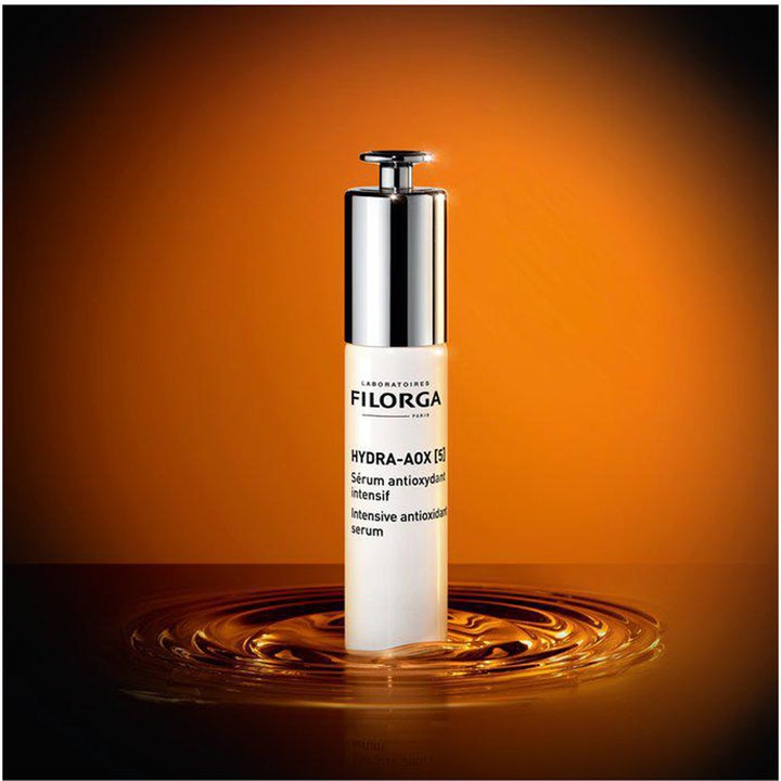 Filorga Hydra-Aox [5] 30 ml antioxidant serum i hvid flaske med sølvpumpe stående i gyldne vandringe