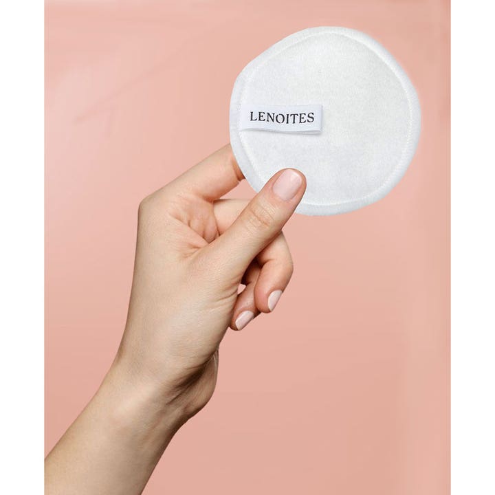 Lenoites Pure Premium Organic Reusable Rounds 5 stk til makeupfjerning er en hvid rondel i en hånd mod pink baggrund