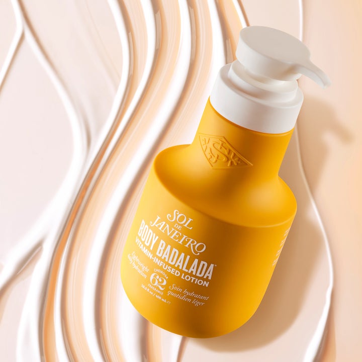 Sol de Janeiro Body Badalada 400 ml vitaminberiget bodylotion i gul pumpeflaske over cremet hvid tekstur