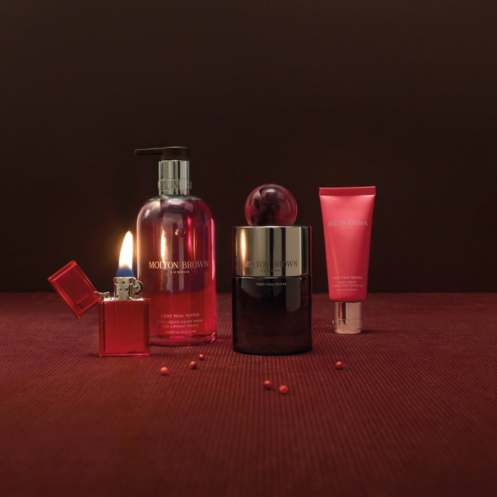 Molton Brown Fiery Pink Pepper Hand Cream 40 ml blødgørende håndcreme i pink tube ved siden af en tændt lighter.