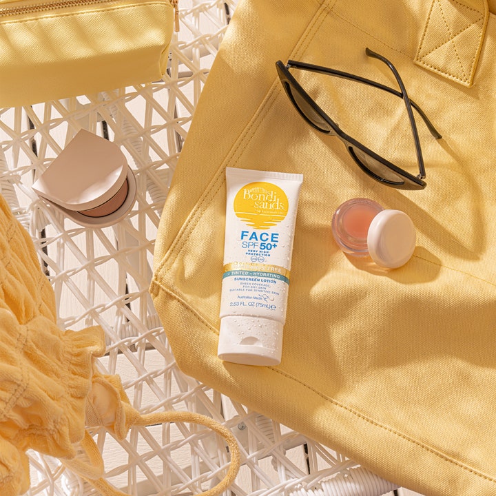 Bondi Sands SPF50+ Hydrating Tinted Face Lotion 75 ml fugtgivende solcreme i hvid tube på gul strandtaske med solbriller.