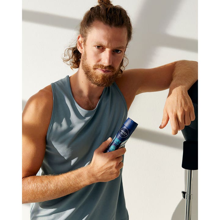 NIVEA MEN Dry Fresh Deospray 150 ml antiperspirant med 72 timers beskyttelse holdt af en mand i grå tanktop