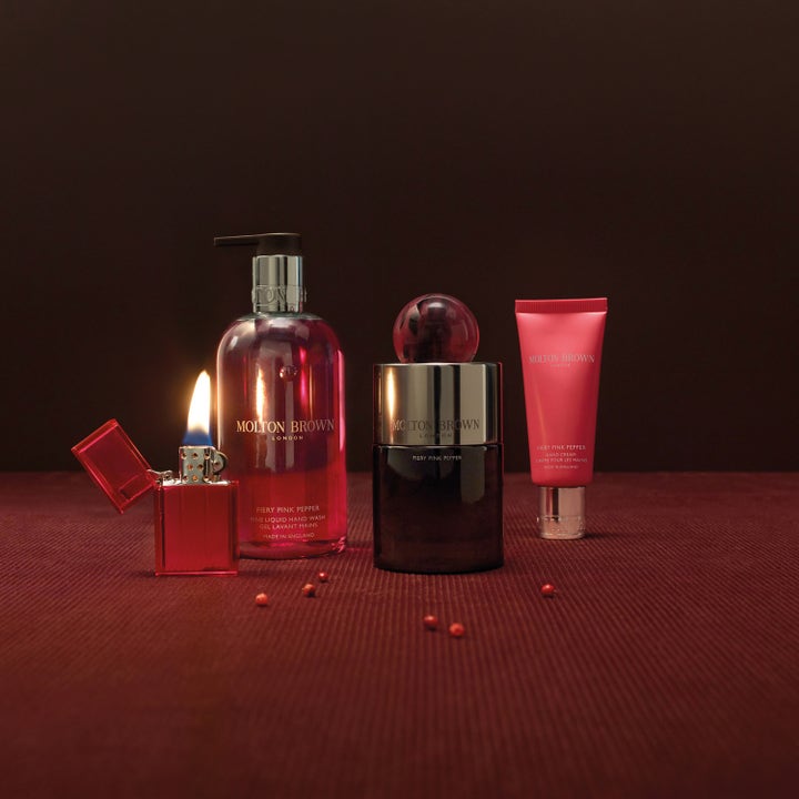 Molton Brown Fiery Pink Pepper 300 ml håndsæbe i gennemsigtig flaske ved siden af en tændt lighter