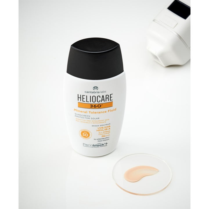 Heliocare Mineral Tolerance Fluid SPF 50 50 ml solcreme til sensitiv hud i hvid flaske med en beige teksturprøve.