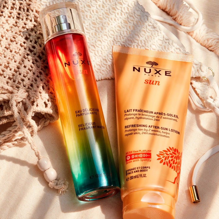 Nuxe Sun kit med 100 ml duftvand og 200 ml aftersun i gradient flaske og orange tube på en lys macramé taske.