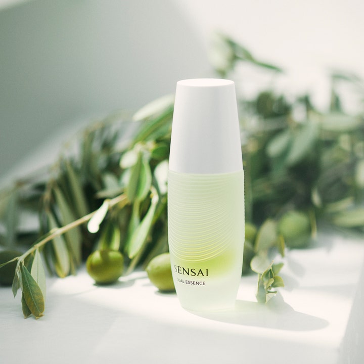Sensai Dual Essence 30 ml plejende ansigtsvand i glasflaske foran olivenkviste og grønne blade