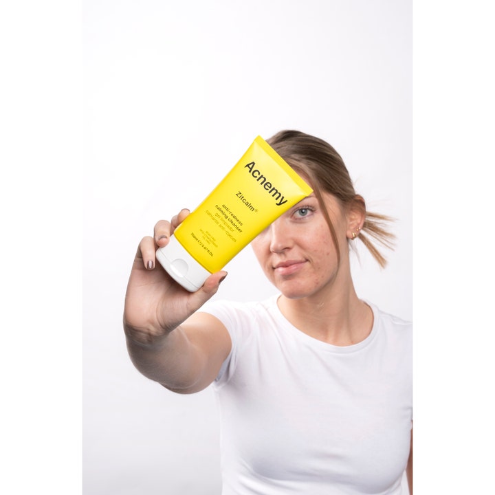 Niche Beauty Lab Acnemy Zitcalm Cleansing Gel 150 ml beroligende ansigtsrens i gul tube holdt af en kvinde
