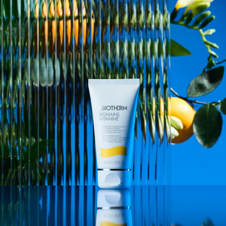 Biotherm Biomains Vitaminé 50 ml fugtgivende håndcreme i hvid tube foran citrusfrugter og blå baggrund.