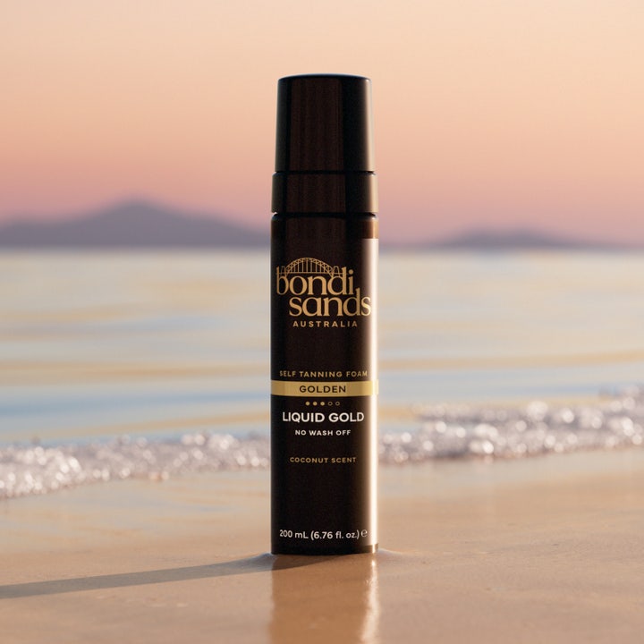 Bondi Sands Liquid Gold Self Tanning Foam 200 ml brun uden sol i sort flaske på en solnedgangsstrand