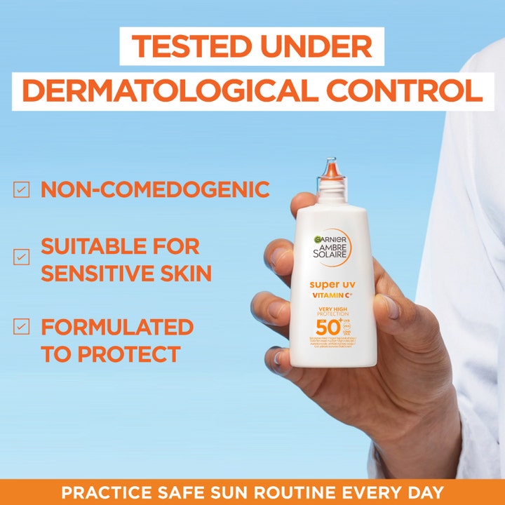 Garnier Ambre Solaire Super UV Vitamin C 40 ml solcreme mod mørke pletter i hvid flaske holdt af en hånd