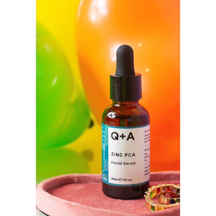 Q+A Zinc PCA Facial Serum 30 ml minimerer porer i mørk glasflaske foran farverige balloner