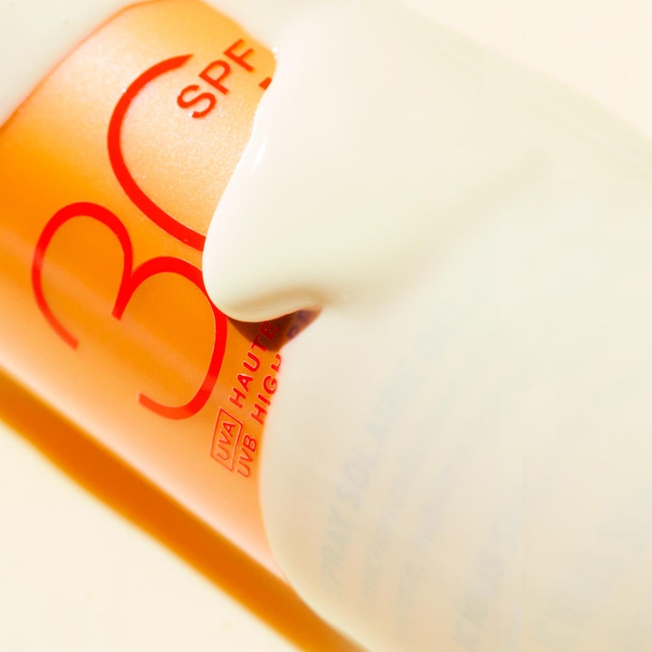 Nuxe Sun Spray SPF30 184 g solcreme til ansigtet med cremet hvid konsistens over orange flaske med rød SPF 30