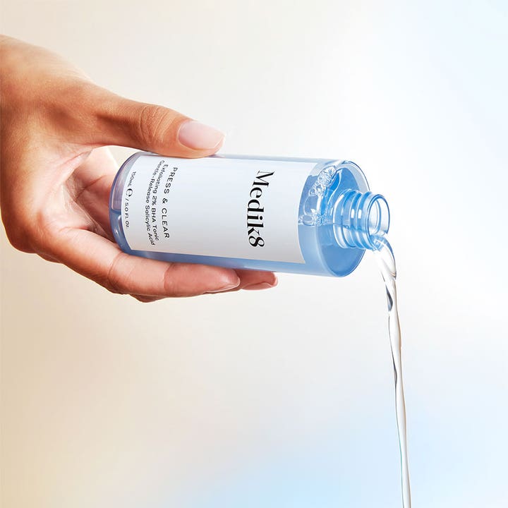 Medik8 Press & Clear 150 ml eksfolierende BHA toner med salicylsyre hældes som klar væske fra blå flaske