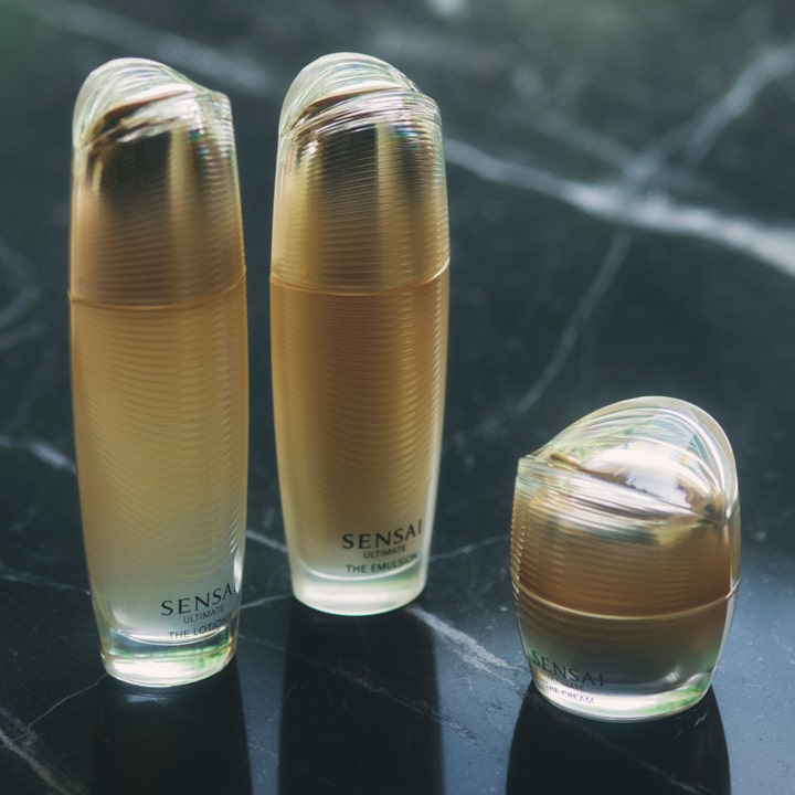 Sensai Ultimate The Cream 40 ml plejende ansigtscreme i guldkrukke vist med lotion og emulsion på marmor.