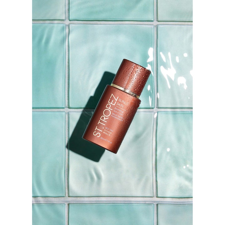 St.Tropez Self Tan Express Sunlit Skin 30 ml brun uden sol ansigtsserum i brun flaske på lyseblå fliser.