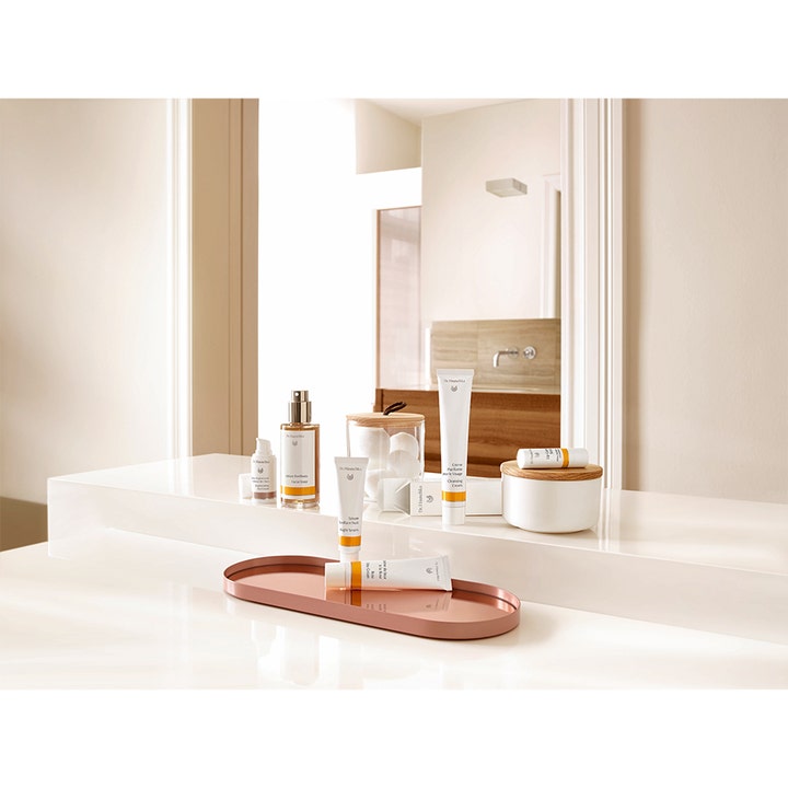 Dr. Hauschka Night Serum 20 ml i hvid tube på et badeværelsesbord sammen med andre hudplejeprodukter