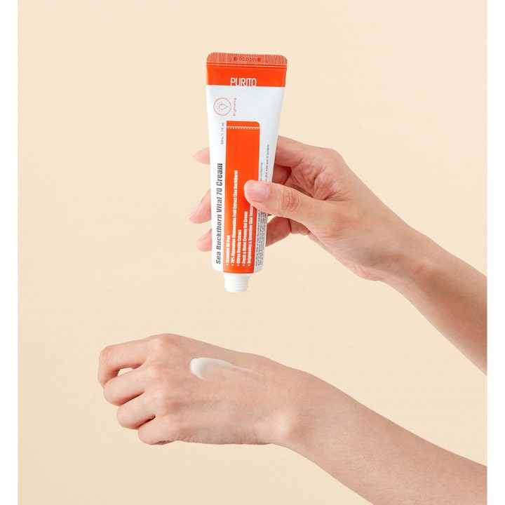 Purito Sea Buckthorn Vital 70 Cream 50 ml lysnende ansigtscreme i hvid og orange tube påført på en hånd.